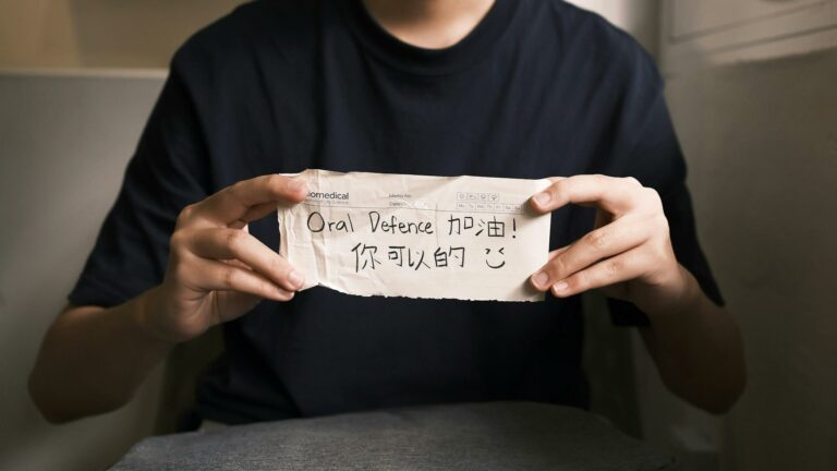 Close-up of hands holding a motivational note for oral defense encouragement.