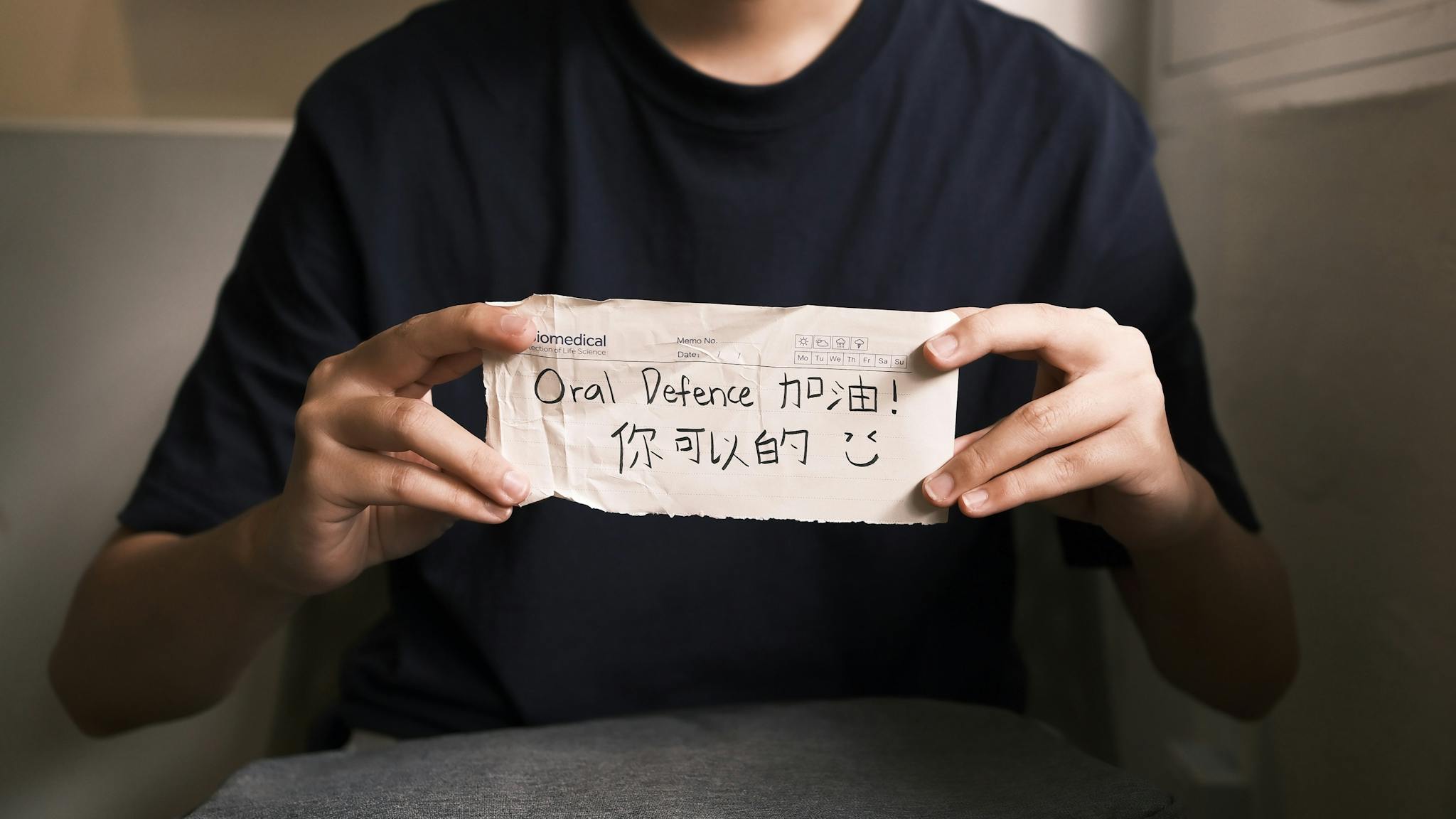Close-up of hands holding a motivational note for oral defense encouragement.