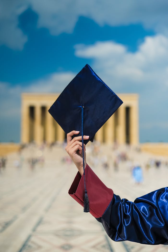 services-04 A graduate holding a cap in front of a blurred architectural background, symbolizing achievement.