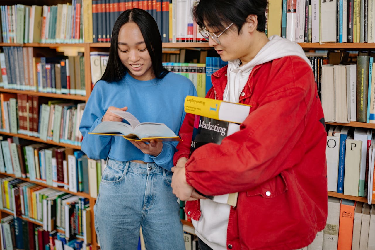 services-02 Two students engaged in collaborative study at a university library, sharing books and ideas.